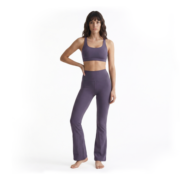Woman wearing purple bootcut leggings on a white background, front view