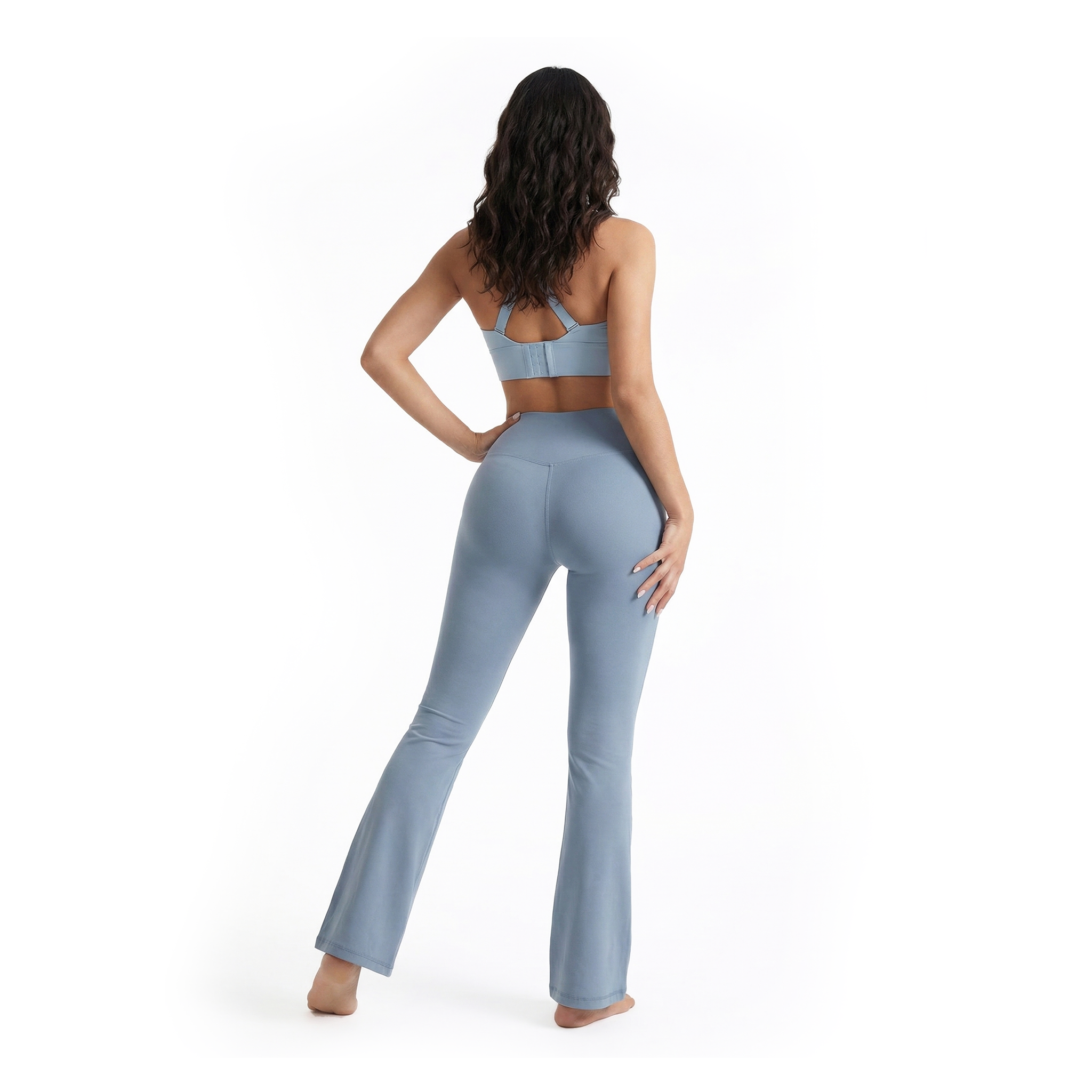 Woman wearing a light blue flared leggings on a white background, back view