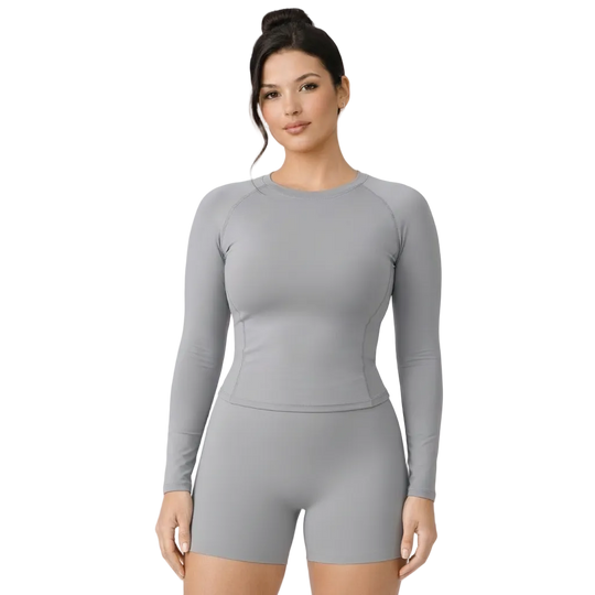 Woman wearing a gray long-sleeve top and shorts set on a light gray background