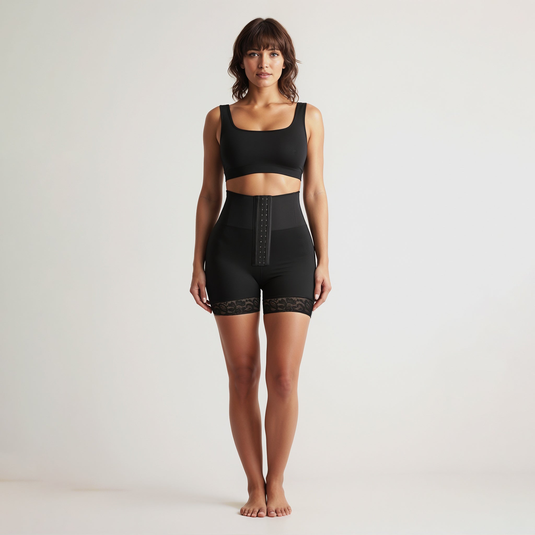 Woman wearing black waist trainer shorts on a plain background, front view