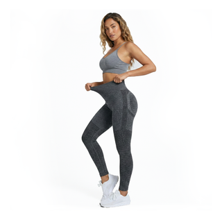 Woman wearing a gray sports bra and leggings on a white background