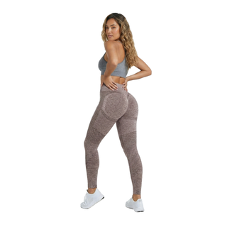 Woman wearing a gray sports bra and brown leggings on a white background