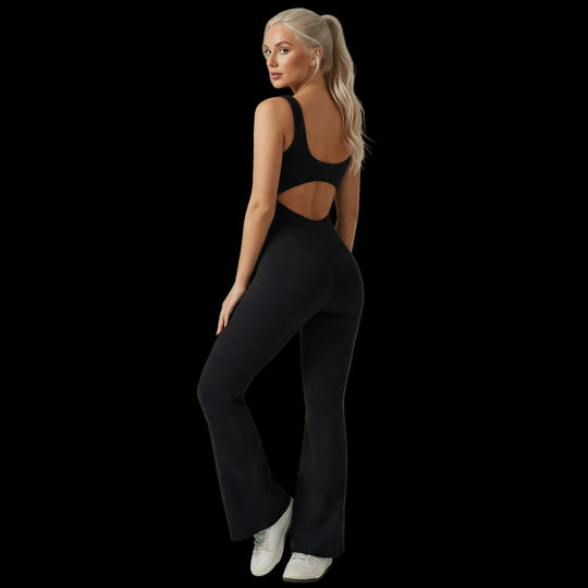 Woman wearing a black jumpsuit with cut-out design on a plain background